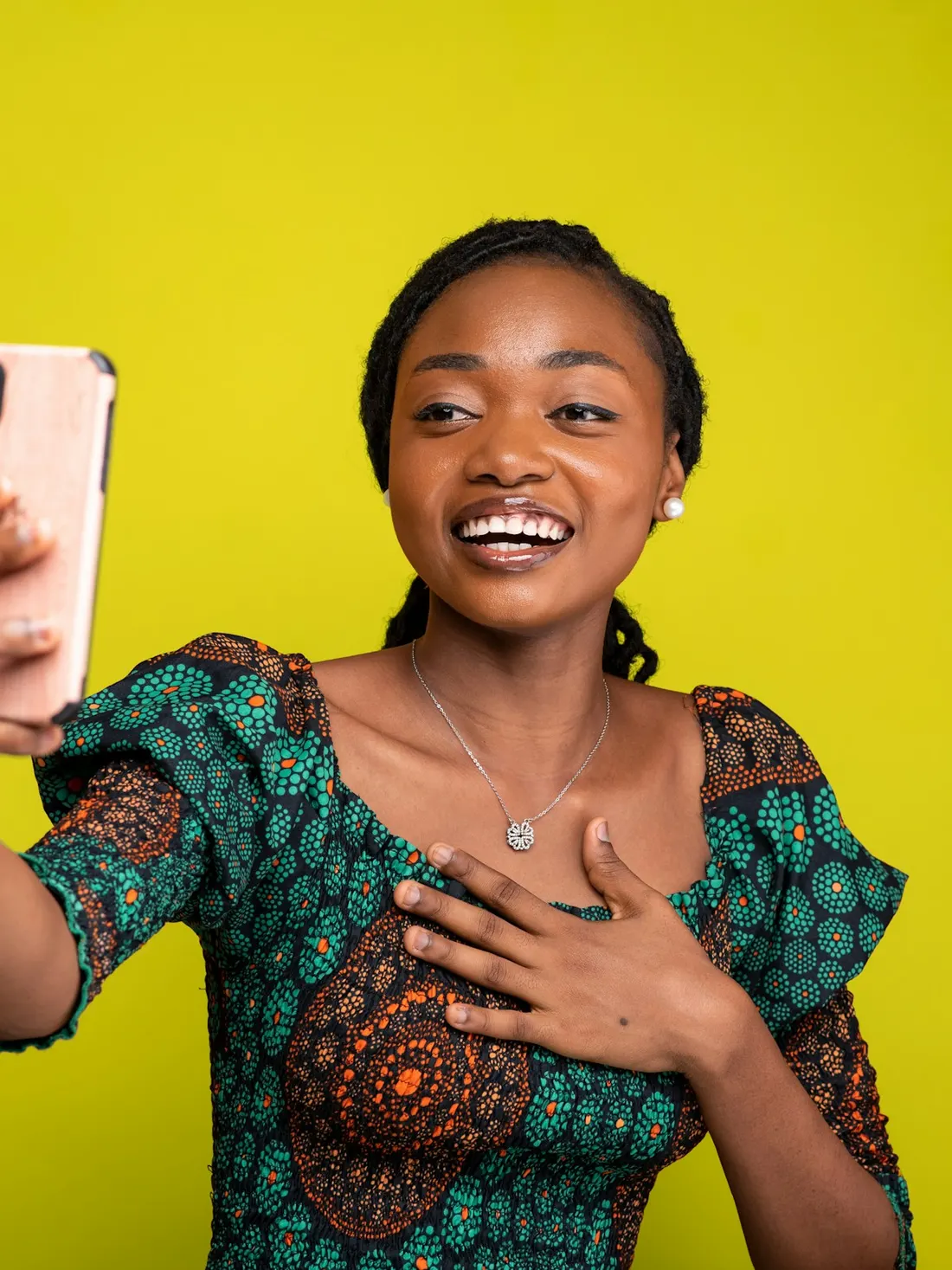 A creator in an Ankara dress filming herself on her phone