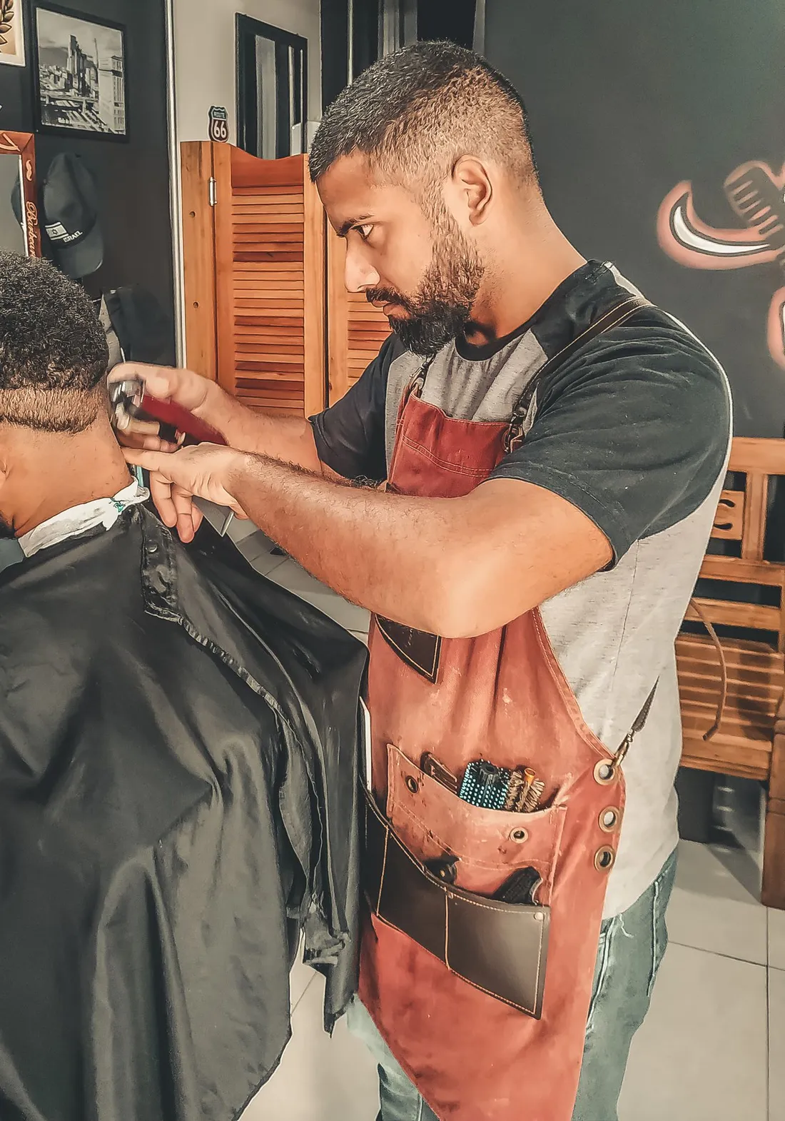 A barber part way through a cut in his shop